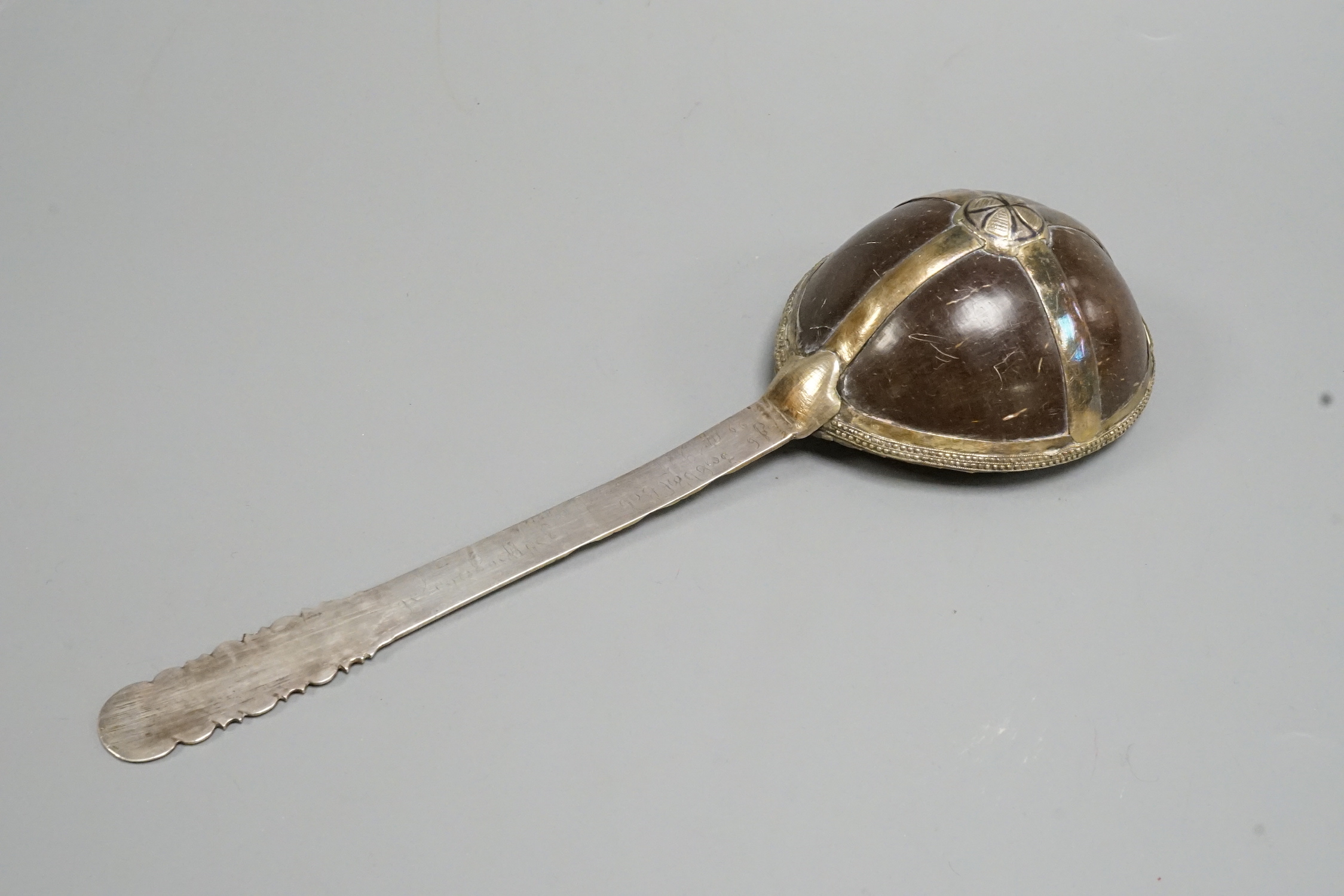 An 18th Russian white and parcel gilt metal ladle, the handle with a niello inlay and a coconut bowl. 28.5cms.